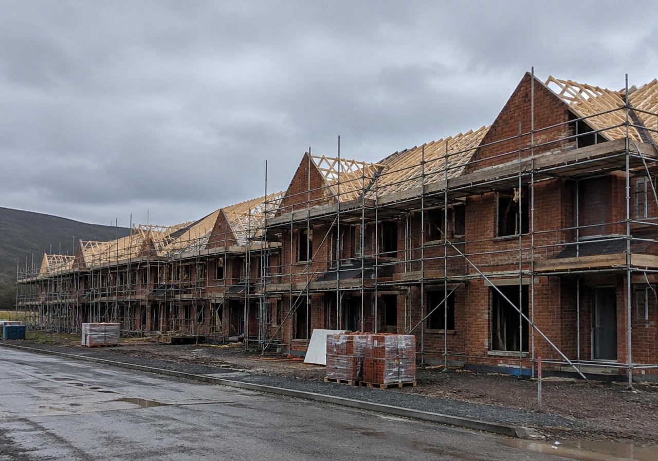 Terrace of new-build brick houses with roof trusses and scaffolding